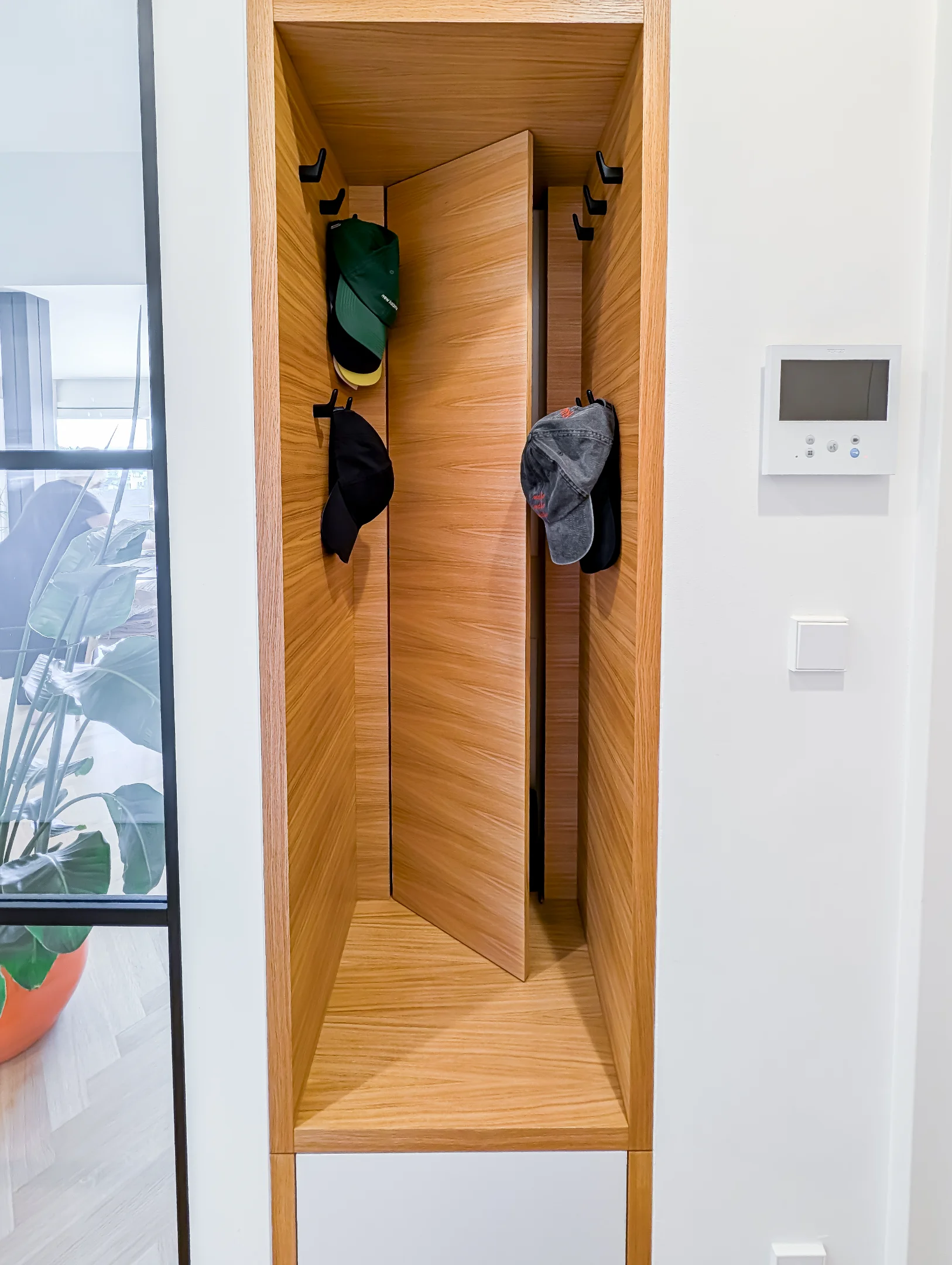 Dřevěná vestavěná skříň s háčky na čepice v interiéru.